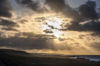 Dramatic cloudy sky with sunbeams at sunset, volcanic coast, La Santa, Lanzarote, Canary Islands,
