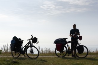 Two e-bikes with luggage bags, cyclist taking a break, back light, Ystad, Sweden