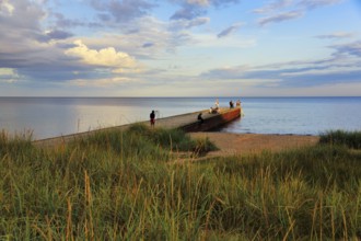 Coastline with beach, grasses on the shore, bathers at the jetty, summer in Ystad, evening sun,