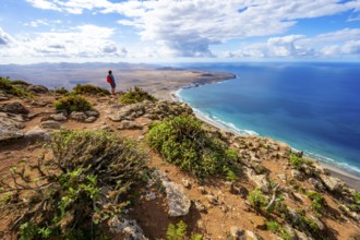 Tourist at Castillejo viewpoint, view from the Risco de Famara cliffs of the coast and the sea with
