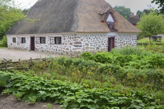 Stone house with thatched roof by older kitchen garden in Den gamle by, The old village, open air