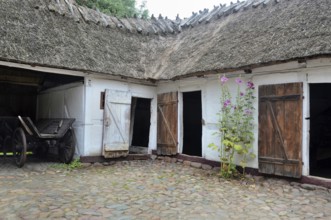 Old farmhouse with thatched roof and stone paving in Den gamle by, The old village, open air museum