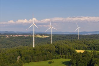 Three wind turbines on a hill in a rural landscape with forests and meadows, near Schorndorf,