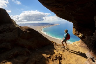 Tourist in the Cueva de las Cabras cave, woman enjoying the view from the Risco de Famara cliffs on