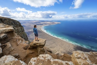 Woman enjoying the view from the Risco de Famara cliffs on Famara beach, Playa de Famara with La