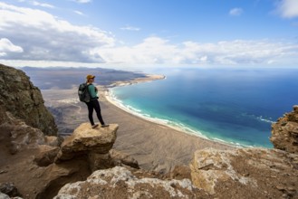 Young woman enjoying the view from the Risco de Famara cliffs to Famara beach, Playa de Famara with