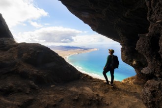 Tourist in the Cueva de las Cabras cave, young woman enjoying the view from the Risco de Famara