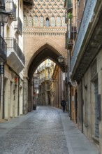 Archway street Mudéjar architecture of Torre de El Salvador church tower, city of Teruel, Aragon,