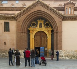 Tour guide and group of people outside Mudéjar door of cathedral church building, city centre of
