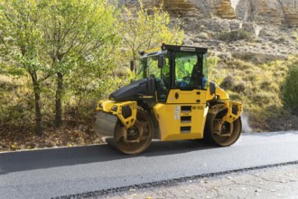 BOMAG compactor machine asphalt road construction resurfacing tarmac in rural area, near