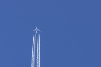 Airbus A380 jet passenger aircraft of Emirates airlines flying in a blue sky with contrails or