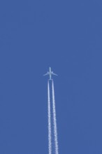 Boeing jet passenger aircraft flying in a blue sky with contrails or vapour trails behind, England,