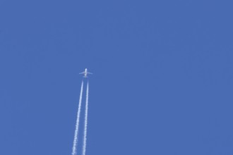 Airbus jet passenger aircraft of Easyjet airlines flying in a blue sky with contrails or vapour