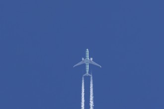 Boeing jet passenger aircraft flying in a blue sky with contrails or vapour trails behind, England,