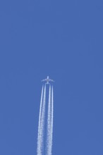 Airbus A380 jet passenger aircraft of Emirates airlines flying in a blue sky with contrails or