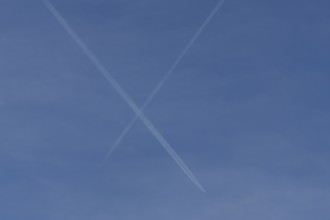 Aircraft contrails or vapour trails crossing in a blue sky, England, United Kingdom