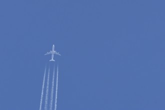Jet passenger airliner aircraft flying in a blue sky with contrails or vapour trails behind,