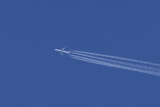 Airbus A340 jet passenger aircraft of Lufthansa airlines flying in a blue sky with contrails or