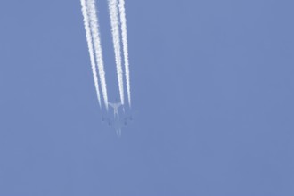 Boeing 747 jumbo jet passenger aircraft of Lufthansa airlines flying in a blue sky with contrails