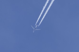 Jet passenger aircraft of Delta airlines flying in a blue sky with contrails or vapour trails