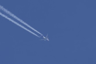 Boeing 777 jet cargo aircraft of FedEx Express airlines flying in a blue sky with contrails or
