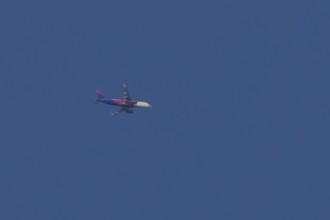 Airbus jet passenger aircraft of Wizz Air airlines flying in a blue sky, England, United Kingdom