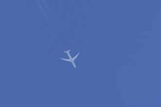 Boeing jet passenger aircraft flying in a blue sky with contrails or vapour trails behind, England,