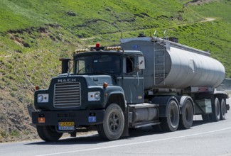 A green truck with a tank trailer is driving on a mountain road, Mack truck with Iranian license