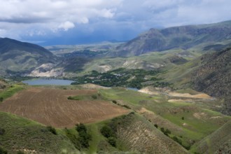 Mountains and valleys with agricultural fields under cloudy sky, landscape with Shamb reservoir
