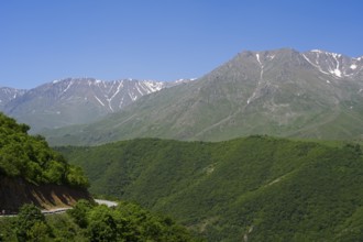 Green wooded hills and majestic mountains under clear blue sky, landscape on M2 near Meghri Pass,