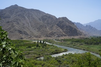 A river crosses a green valley surrounded by rugged mountains, view of Iran, Aras river near