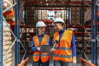 Two diverse female workers collaborating and verifying stock levels with a barcode scanner and