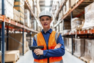 Woman logistics professional wearing a safety hard hat and high visibility vest, holding a barcode
