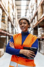 Confident black woman worker wearing a hardhat and high visibility vest, holding a barcode scanner