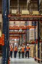 Diverse logistics team standing together in a large modern distribution warehouse, supervising