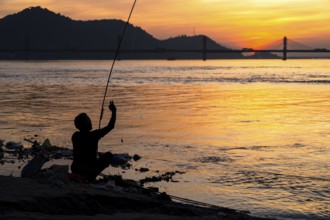 A person fishing in the river Brahmaputra during sunset, on November 4, 2025 in Guwahati, India