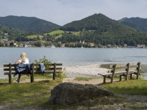 View of Tegernsee with castle, woman sitting on a bench, Bad Wiessee, Upper Bavaria, Bavaria,