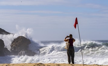 Tourists watch the waves of the Atlantic on the rocky plateau of Sito, also known as Forte São
