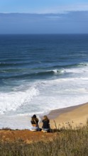 Tourists watch the waves of the Atlantic on the rocky plateau of Sito, also known as Forte São