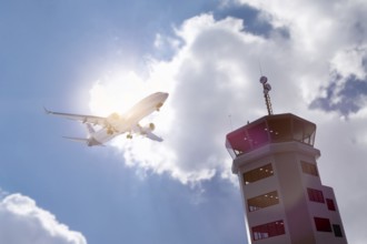 Air traffic control tower at airport as airplane takes off