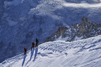 Three ascended mountaineers run across a snow-covered mountain ridge, Aiguille du Midi,