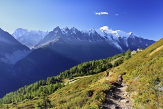Female hiker on a hiking trail with the La Flégère cable car mountain station and the snow-covered