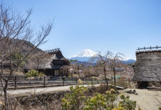 Iyashinosato open-air museum, old Japanese village with traditional houses, at the back volcano Mt.