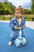 Cheerful toddler riding a balance bike in a vibrant playground, developing motor skills and