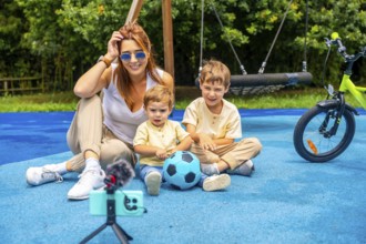Influencer mother vlogging with her two children at the playground, capturing joyful moments with a