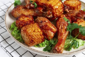 Fried chicken drumsticks, Mexican style, with corn, on a plate, close-up