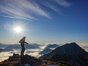 Mountaineer looking at blue-colored silhouette of mountains, fog in the valley, Hochstaufen,