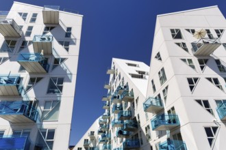 Distinctive white residential complex, turquoise balconies against blue sky, pyramid-shaped
