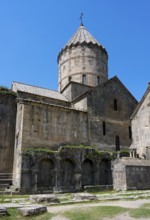 Monumental monastery complex with characteristic tower and stone architecture under a blue sky,