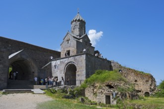 Historic stone church with ruins and grassy areas under clear blue sky, Tatev monastery, Armenian